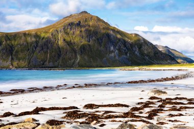 Kristal turkuaz suyla yıkanmış beyaz kumlar. Norveç, Lofoten Adaları 'ndaki Ramberg plajından deniz manzarası