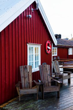 Nusfjord limanında renkli kırmızı balıkçı evleri ve Norveç 'in Lofoten Adaları' nda huzurlu bir akşamda yelkenli tekneleri var.