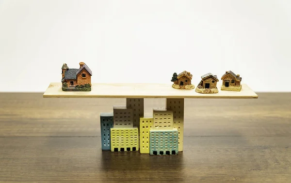 Big orange house balance with three small houses based on buildings