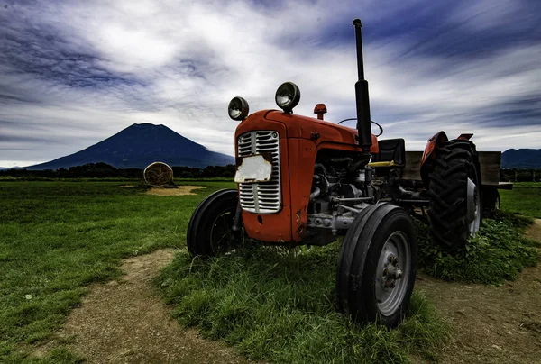 红色老拖拉机在领域与山背景 — 图库照片