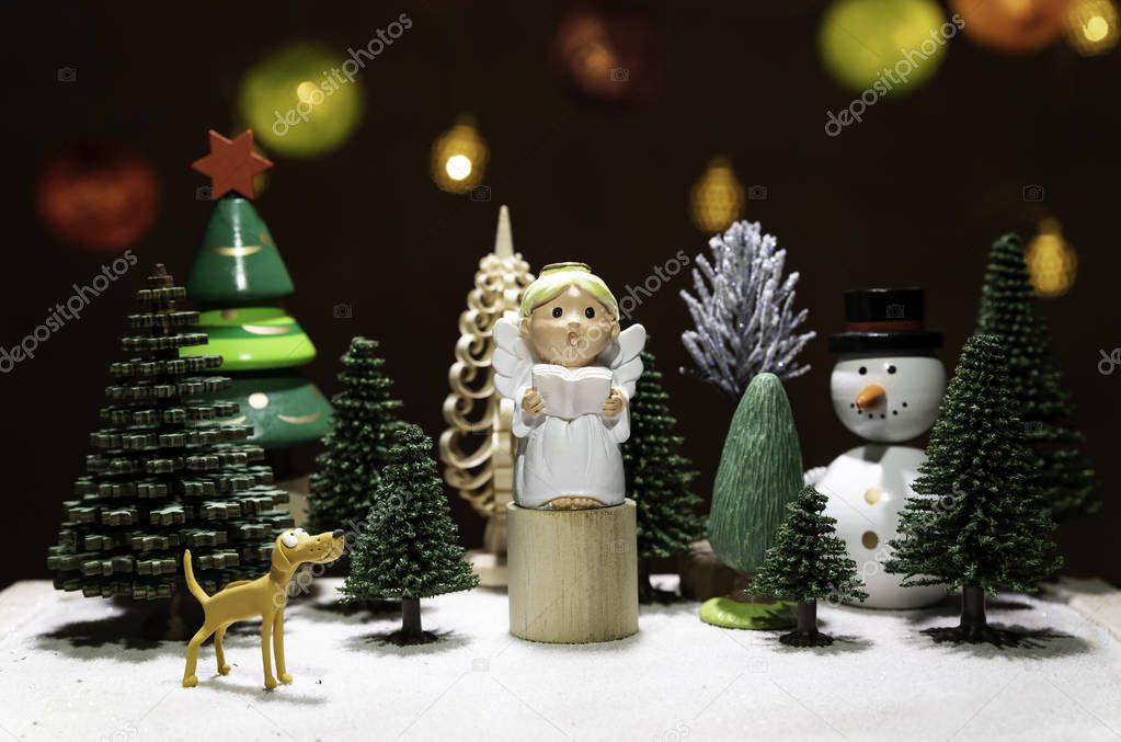 Small Angel read a book on circle wooden chair with dog watching and snow man isolated from Christmas light background