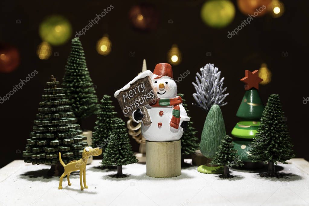 Snowman on circle wooden chair with dog watching among Christmas tree