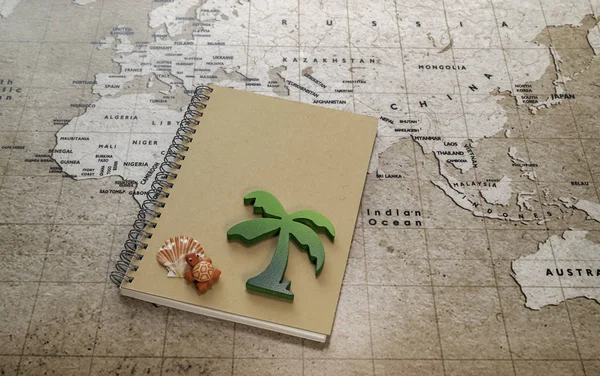 Dünya haritasında dizüstü bilgisayarüzerinde deniz kabuğu ile yeşil ahşap palmiye ağacı ve kırmızı kaplumbağa