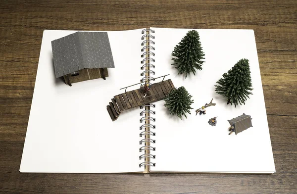 白い空白のノートに松の木 橋と家とキャンプ2つのミニチュア — ストック写真
