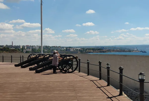 Woman and vintage guns on the background of the sea