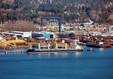 Terminal North Vancouver liman dağ manzarası bir arka plan üzerinde. Gemi yük altında römorkör başka bir gemi çekiyor.