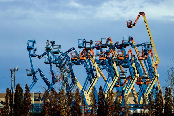 Rental construction  equipment. Boom lifts  with raised platforms are on-site on   for the equipment for rent