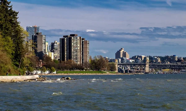 Skyline  of Vancouver city at Vancouver Harbor ,  Downtown and Stanley Park on the background of a blue stormy sky