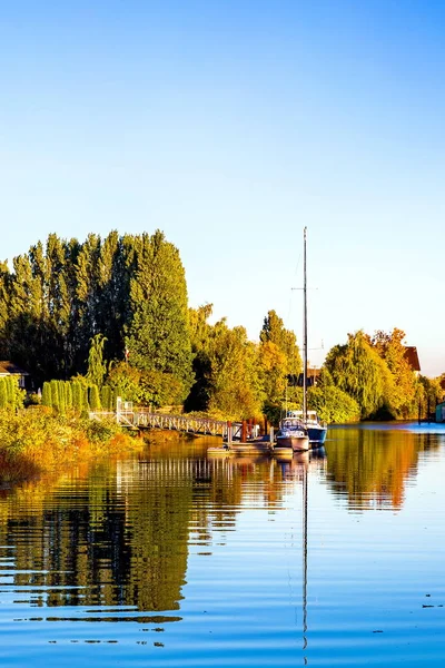 秋天的时候 码头附近的河岸上长满了泛黄的树木 两艘游艇在蓝天上停车 — 图库照片