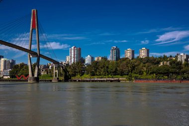 Fraser Nehri üzerinde Surrey ve New Westminster bağlayan Sky-tren köprü, karşı kıyısında şehir, bir arka plan üzerinde beyaz bulutlar ile mavi gökyüzü 