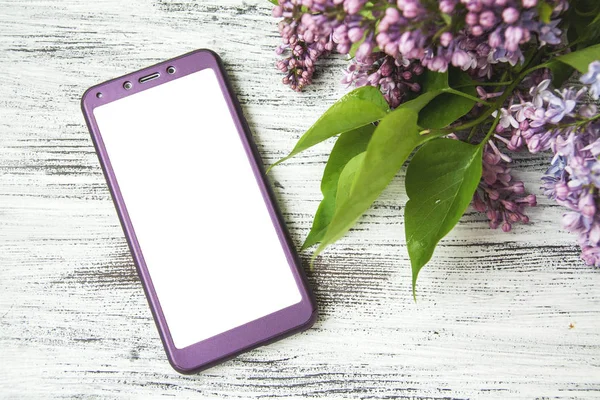 ahşap masa ve leylak çiçekler üzerinde akıllı telefon