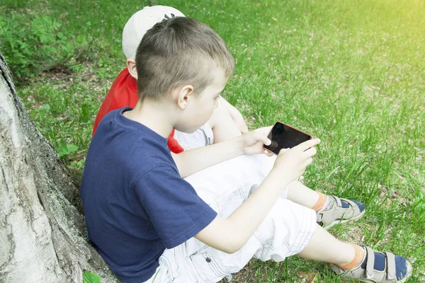 çocuklar yeşil çim üzerinde smarfon oynuyor