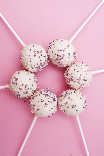 Dessert on a stick (cackes-pop) with powder on a pink background