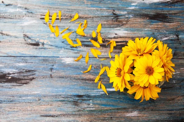 Flores amarelo-alaranjadas com pétalas em uma mesa de madeira vintage . — Fotografia de Stock