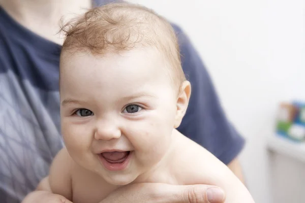 Bayi kecil yang sehat dan ceria tersenyum dalam pelukan ayahnya — Stok Foto