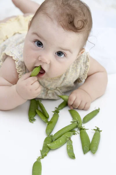 白い背景にエンドウ豆を持つ小さな子供 — ストック写真