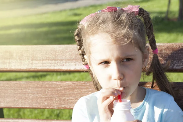 Egy kislány iszik egy koktélt egy forró, napsütéses napon egy padon i — Stock Fotó
