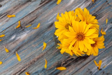 Bir vintage ahşap masada yaprakları ile sarı-turuncu çiçekler.
