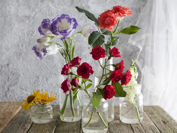 Flores en jarrones-tarros sobre una mesa de madera —  Fotos de Stock