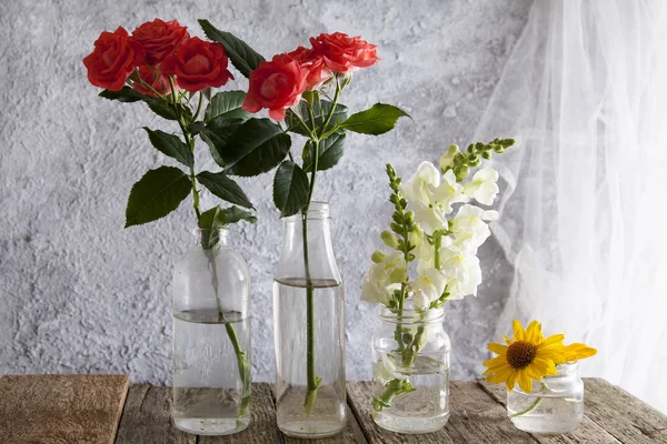 Flores en jarrones-tarros sobre una mesa de madera —  Fotos de Stock