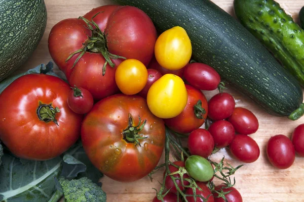 Düz bir masa üzerinde taze büyük ve küçük domates ve sebze — Stok fotoğraf
