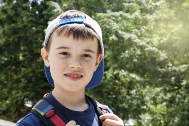 yeşillik ve güneş arka planda bir sırt çantası ile sevimli çocuk