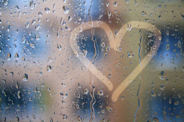 Raindrops on the window with a heart pattern - concept photo abo — Stock Photo, Image