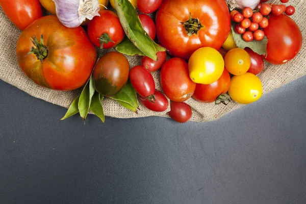 Tomatoes on a black background with burlap with place for text. — Stock Photo, Image