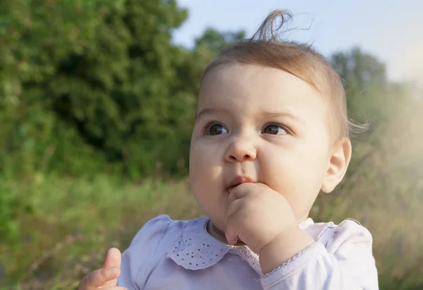 Divertente bambina tiene le dita in bocca su uno sfondo di — Foto Stock