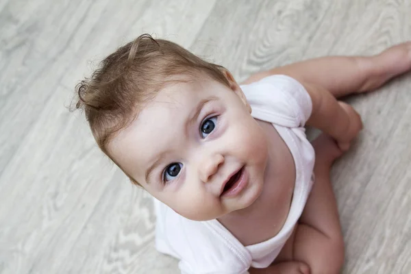 Маленький ребенок в возрасте до одного года сидит на полу и улыбается — стоковое фото