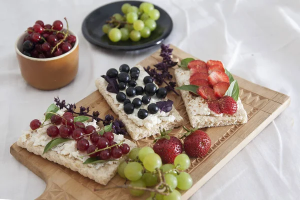 summer breakfast in bed with sandwiches with cheese and berries