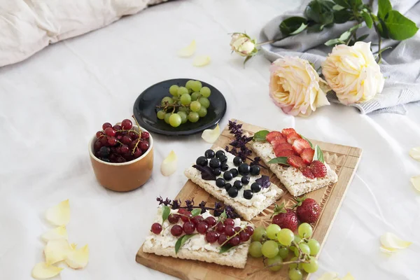 summer breakfast in bed with sandwiches with cheese and berries