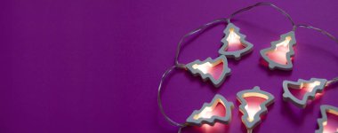 Pembe bir arka plan w üzerinde beyaz ahşap ağaçlar ile Noel çelenk