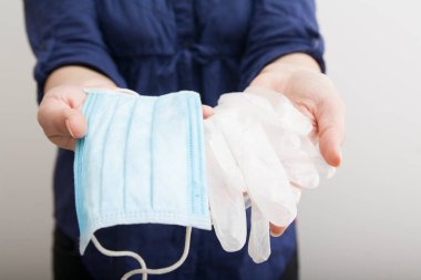 Tıbbi maske ve eldivenler bir kadın eli tarafından tutulur. Karantina koruma kavramı