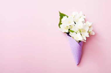 Pembe arka planda yasemin çiçekleri olan mor waffle dondurma külahı. Kopyalama alanı olan yaz konsepti