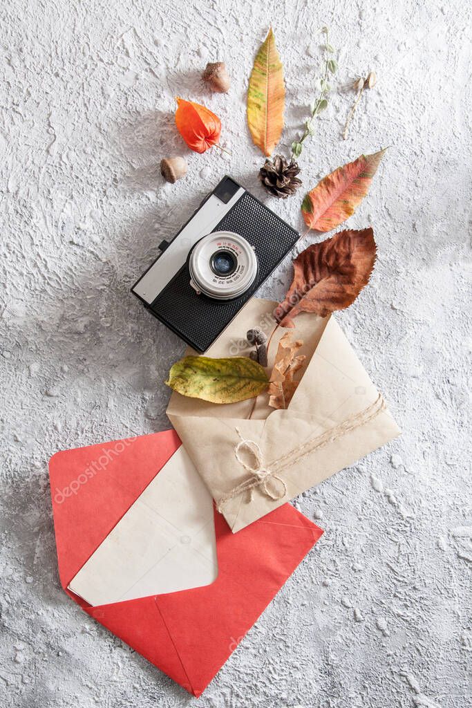 Top view of layout with vintage camera, envelopes and fallen leaves. Autumn concept