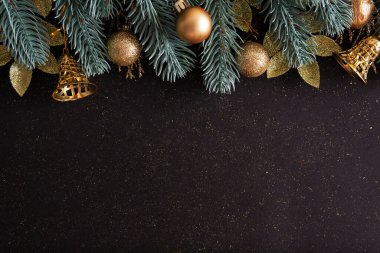 Noel ağacı, altın takılar ve fotokopi alanı olan siyah bir arka planda çanlar. Yeni yıl için en iyi kompozisyon Kış selamları