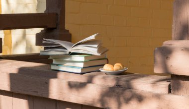 Kitaplar ve bir tabak kruvasan ağaçların gölgesinde verandada. Okumak ve dinlenmek için rahat bir yer.