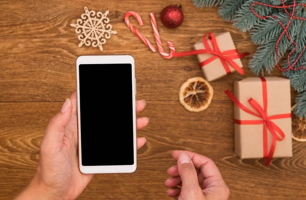 クリスマスの装飾の背景に女性の手にフラットレイスマートフォンのモックアップ 新年のオンラインショッピング ロイヤリティフリーのストック画像