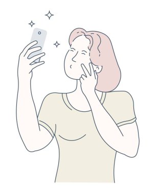 Genç bir kadın akıllı telefonuyla selfie çekiyor.