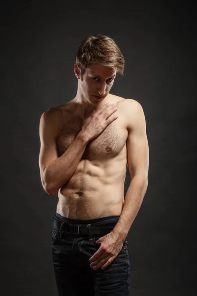 Ολόσωμο πορτραίτο ενός σέξι νεαρού άντρα με τζιν και ημίγυμνος που ποζάρει στο στούντιο. — Φωτογραφία Αρχείου