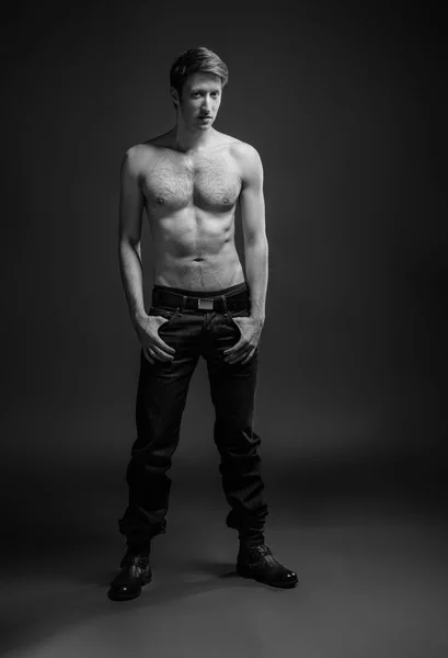 Retrato de comprimento total de um jovem sexy em jeans e sem camisa posando no estúdio . — Fotografia de Stock