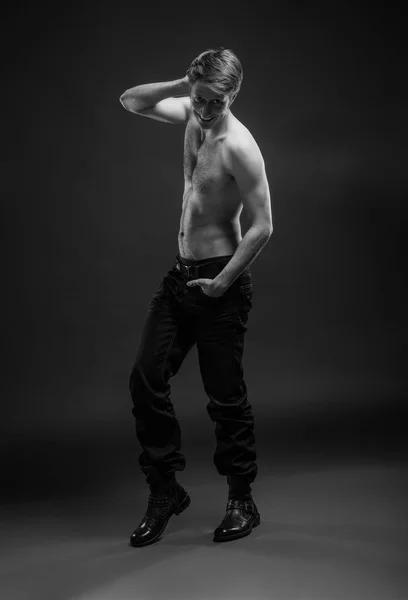 一个性感的年轻人在牛仔裤和无衬衫的姿势在工作室的全长肖像. — 图库照片