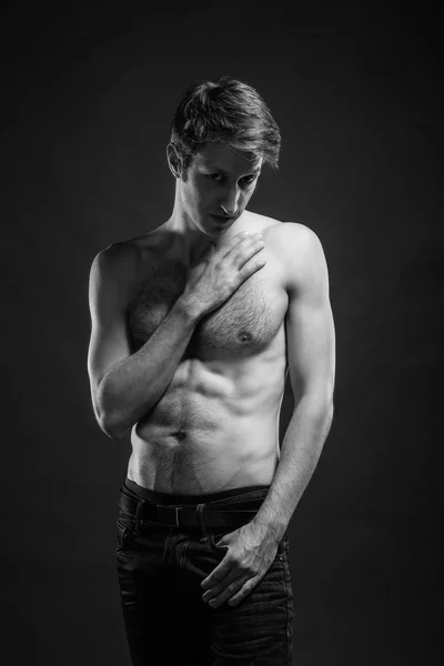 Retrato de cuerpo entero de un joven sexy en jeans y sin camisa posando en el estudio . — Foto de Stock