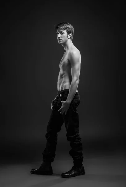 Retrato de cuerpo entero de un joven sexy en jeans y sin camisa posando en el estudio . — Foto de Stock