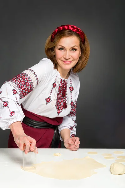 Mujer adulta en estilo tradicional ucraniano. Cocinar varenyky ucraniano con cerezas. Serie. —  Fotos de Stock