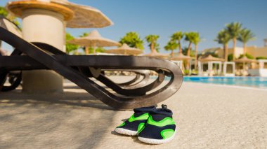 pare of shoes at swimming pool background at morning sun clipart