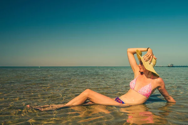 海岸の地平線の海の中に敷設の帽子の若い白人女性 — ストック写真