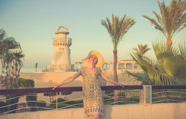 Genç kadın rahatlatıcı günbatımı deniz kıyısında arka plan, balkon