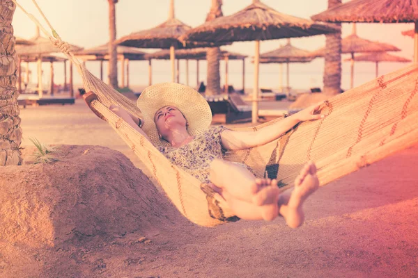 pretty joyful woman on hammock at sunset beach